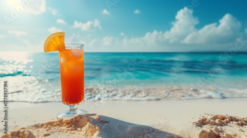 Bright orange tropical cocktail in tall glass on sandy beach