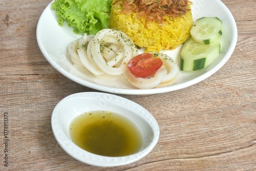 slice boiled squid and biryani rice cooked with curry on plate dipping sweet chili sauce  