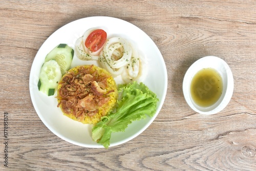 slice boiled squid and biryani rice cooked with curry on plate dipping sweet chili sauce  