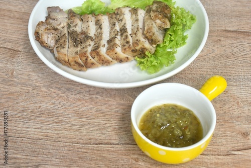 grilled slice salty pork loin with black pepper topping lettuce on plate dipping spicy hili sauce cup