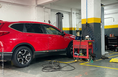 Obraz na plátně Taller mecánico con coche rojo en revisión y reparación