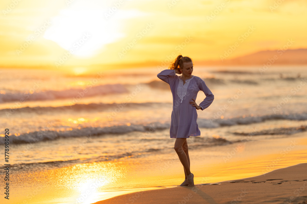 Fototapeta premium Woman enjoying golden sunset on tropical beach