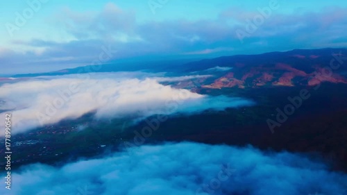 Aerial footage of a rural mountainous area covered in a layer of fog on an autumn morning