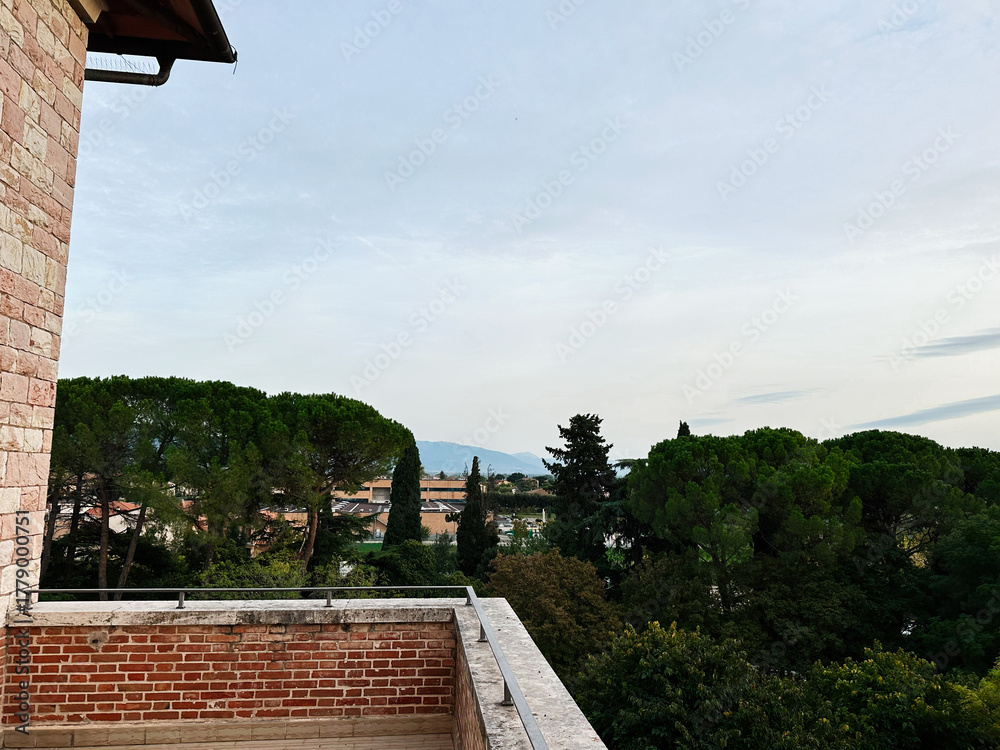 Obraz premium Assisi Italy terrace view with brick railing and lush trees overlooking town from a stone building