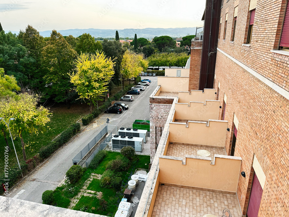 Obraz premium Assisi Italy residential building balcony view with trees and street below