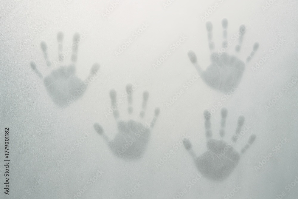 Obraz premium Three handprints on foggy glass surface with soft light and mist