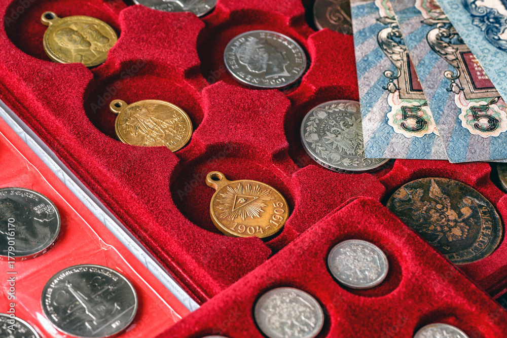 Fototapeta premium Numismatics.Antique collectible coins made of silver and gold on the table.Coins in the album.Collection of ancient coins and banknotes.Magnifying glass.Bonistics.Antikvariat.