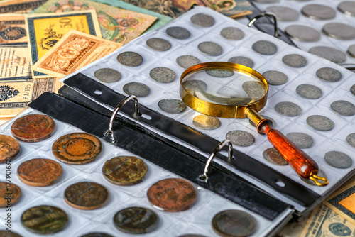 Numismatics.Antique collectible coins made of silver and gold on the table.Coins in the album.Collection of ancient coins and banknotes.Magnifying glass.Bonistics.Antikvariat.