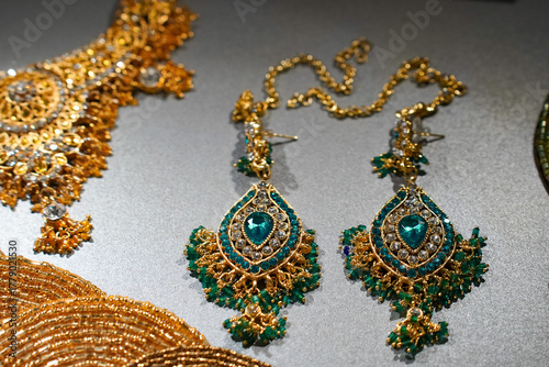 Vintage luxury Indian gold earrings with exquisitely shaped green gemstones harmoniously complement exquisite jewelry