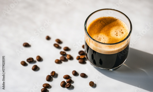Hot espresso coffee steam rises from hot coffee in coffee glass and bean isolated on white background in Morning sunlight