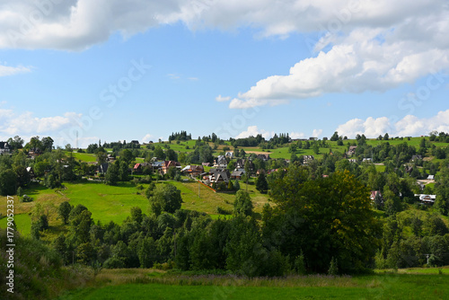 Mountainous rural landscape with hills, fields, trees and residential houses. Podhale, Poland