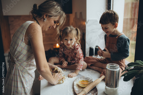 A mother and her children are preparing delicious food in the kitchen on the eve of the holiday. Children and their mother are cooking