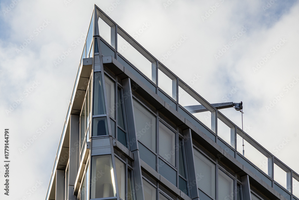 Fototapeta premium Sharp Angular Corner of a Modern Building Against a Cloudy Sky