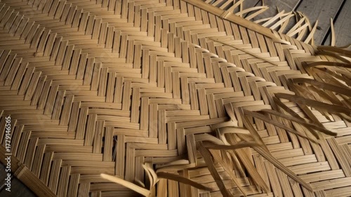 Close-up of woven natural fiber with intricate crisscross pattern. Some loose strands visible. Wooden surface