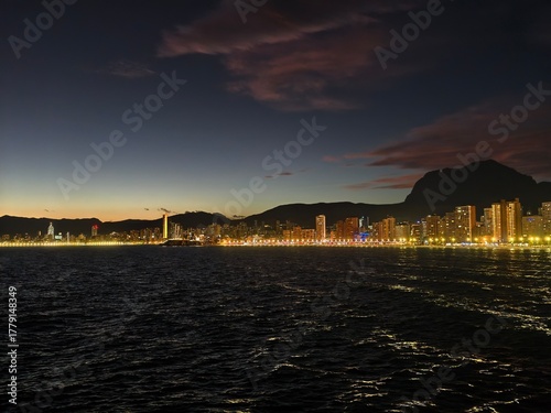 Canvas Print evening glow over distant mountains, twilight scene with illuminated shoreline a
