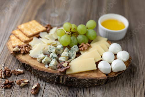 Gourmet cheese board with grapes and crackers on rustic wood background