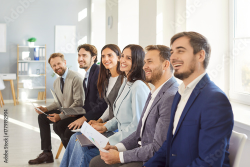 Tableau sur toile Young smiling applicants sitting in line, queue preparing for interview in moder