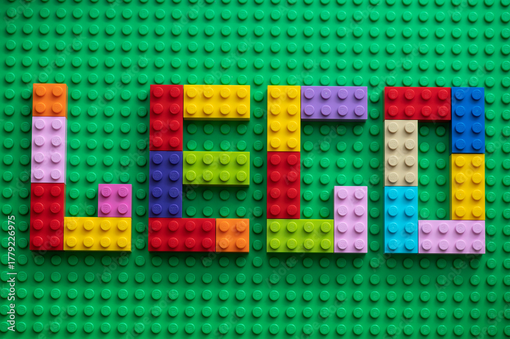 Naklejka premium Colorful plastic building blocks spelling the word Lego on green background