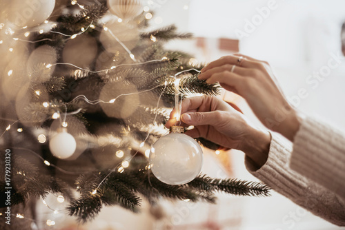 Closeup of woman hands decorating Christmas tree at home, winter holiday and xmas time concept