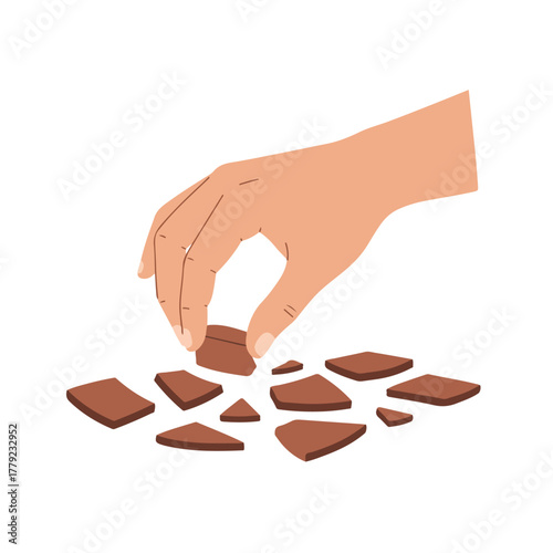 A hand reaching down to pick up a single brown piece from a scattering of similar shaped brown pieces