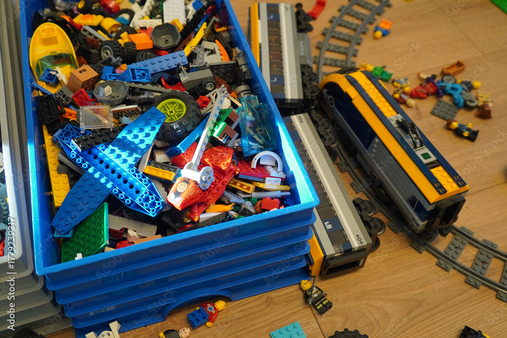 Naklejka premium A collection of colorful Lego bricks and train sets on a wooden surface