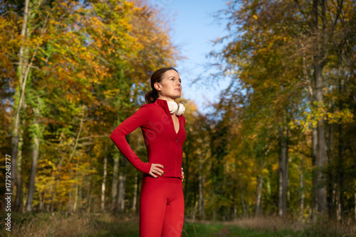 fit sporty woman with hands on hips after running and exercise outdoors in a forest with headphones