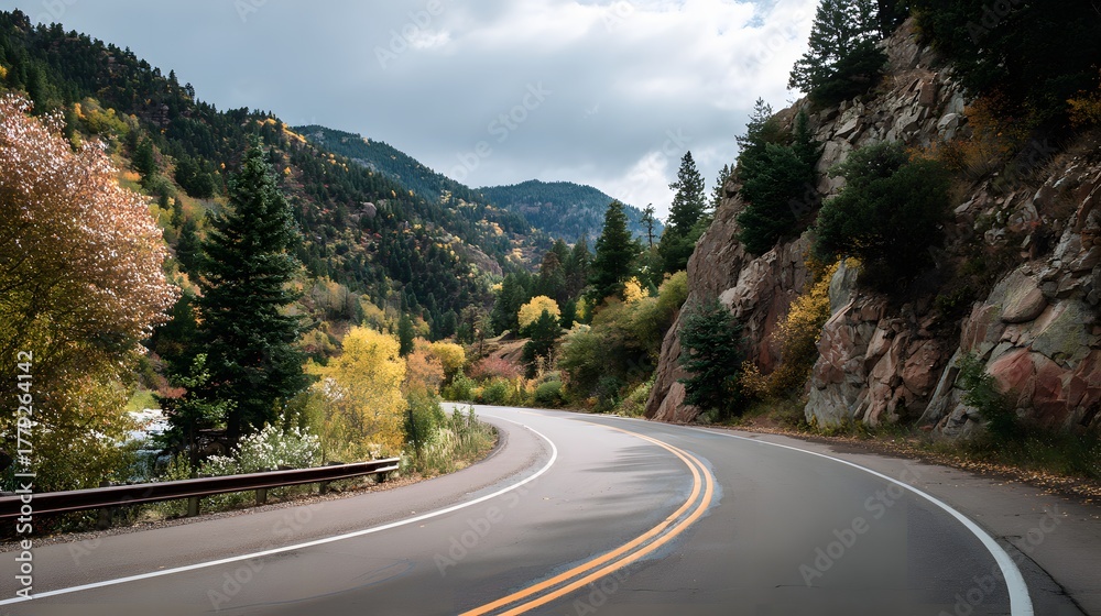 Fototapeta premium Winding mountain highway curves through a forested landscape during the autumn season