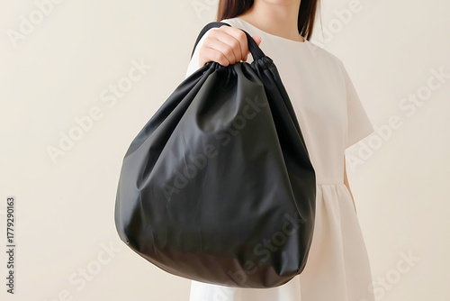 Person holding a sleek black drawstring bag, ideal for carrying everyday essentials, shopping, or gym gear with minimalist style.