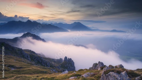 Majestic sunset over a sea of clouds, revealing a stunning mountain range with rocky foreground.