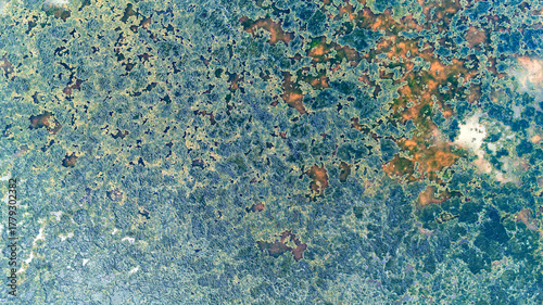 Closeup aerial texture of a swamp lake surface dominated by blue and green hues from algae and water reflections creating an impressionist painting style natural image