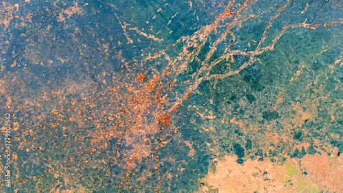 Top down view of orange and brown muddy water in a swamp mixing with dark blue currents creating a fiery and dramatic abstract texture pattern from a drone perspective