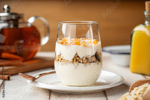 Healthy yogurt dessert served in a glass with granola, dried fruits and apricot jam, topped with almond flakes