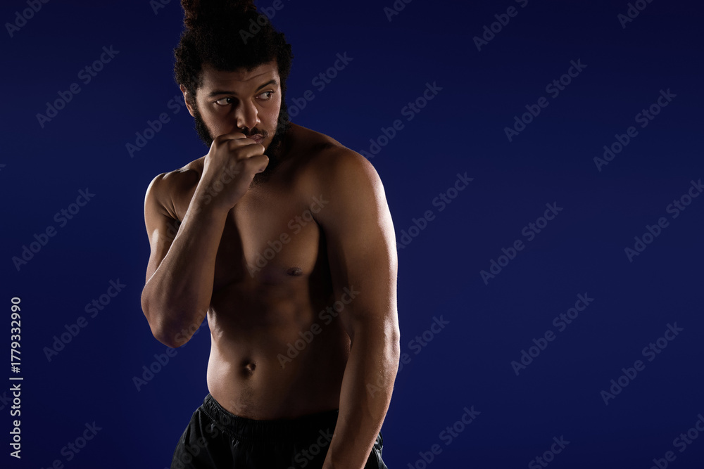 Fototapeta premium Sportive man engaging in workout on a vibrant blue background with confident expression