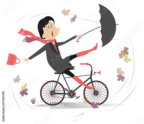 Windy and rainy weather.
Woman with an umbrella rides a bike under strong wind and rain
