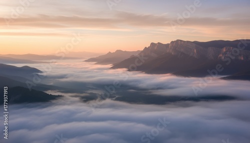 Majestic mountain range emerging from a sea of clouds at sunrise.
