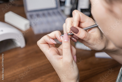 Womans hands performing a manicure by oneself with cuticle pusher, emphasizing personal beauty, nail care, at-home treatment, and relaxing DIY routine