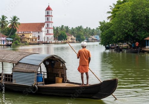 Traditional boatman poling a houseboat on serene backwaters with a church in the background.
