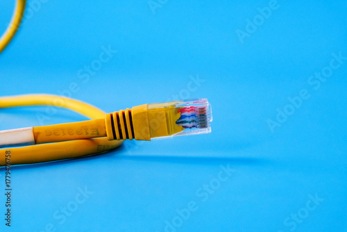Yellow RJ45 Ethernet cable on color background.
