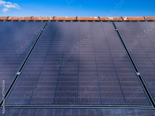 Close-up of residential solar panels on a house roof under a clear blue sky in the UK, capturing clean power and modern home efficiency.