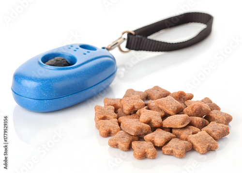 Blue training clicker sits near pile of star shaped dog treats on a white surface top view