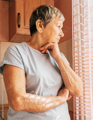 Elderly caucasian woman thoughtfully looking out of window