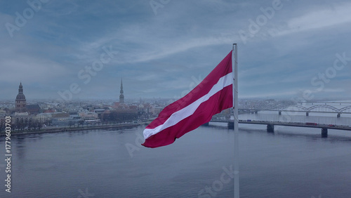 Drone View Of Riga Old Town With Latvian Flag Waving In Foreground Aerial Panorama Of Historic City Center, Daugava River And Urban Skyline On A Outumn Day In Latvia