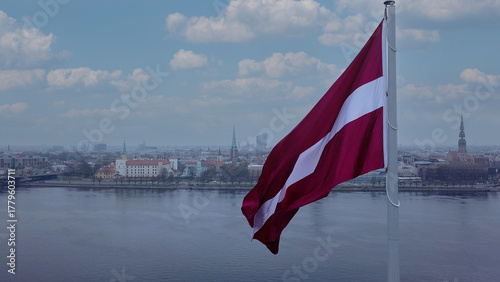 Drone View Of Riga Old Town With Latvian Flag Waving In Foreground Aerial Panorama Of Historic City Center, Daugava River And Urban Skyline On A Outumn Day In Latvia