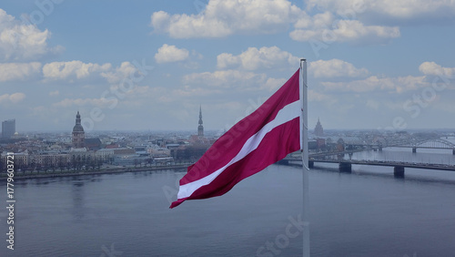 Drone View Of Riga Old Town With Latvian Flag Waving In Foreground Aerial Panorama Of Historic City Center, Daugava River And Urban Skyline On A Outumn Day In Latvia