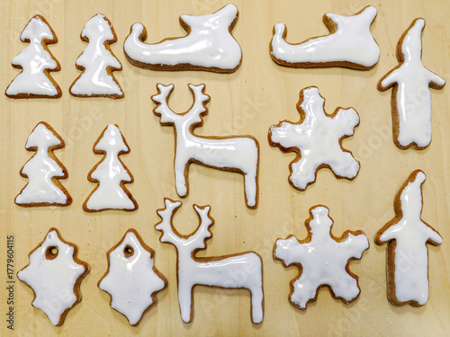Seasonal shaped gingerbread cookies with white icing shot from above on wooden surface