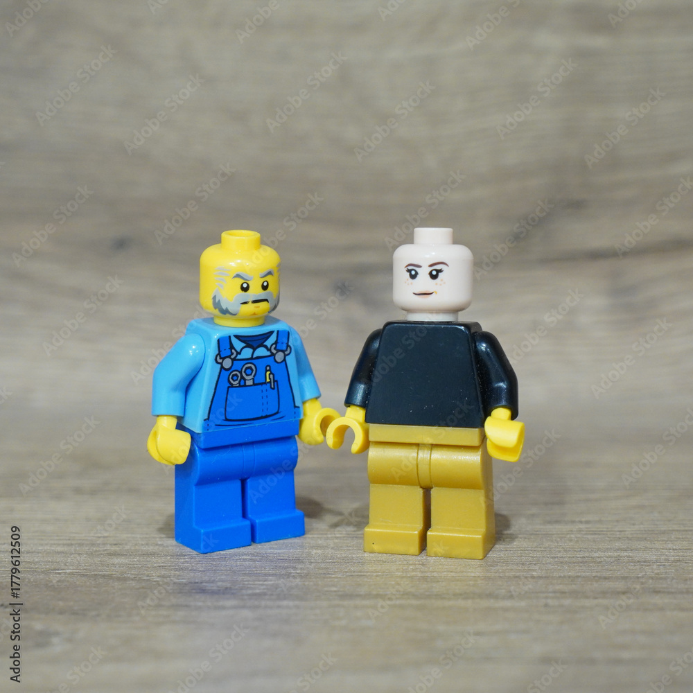 Naklejka premium Two Lego minifigures standing together on a wooden surface
