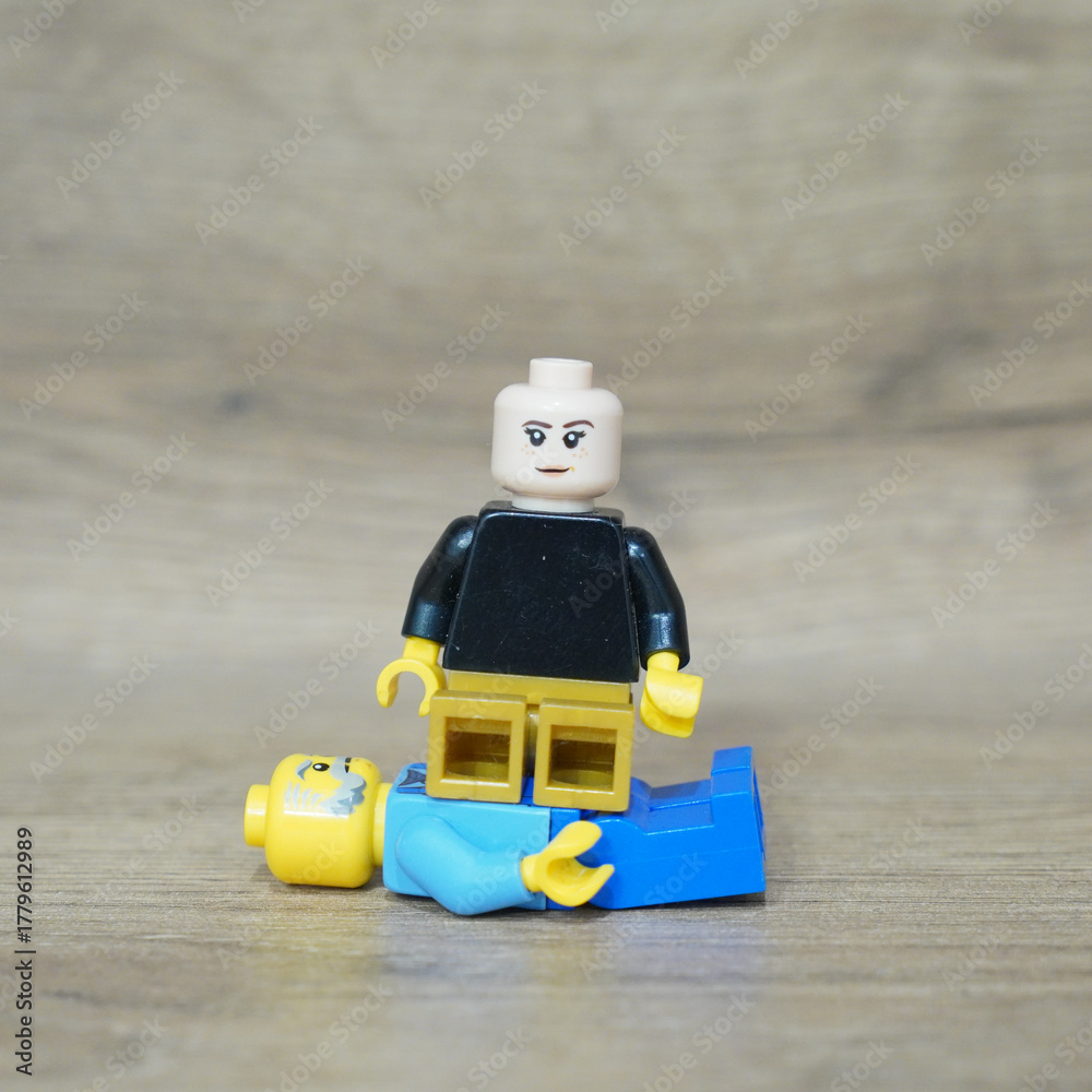 Naklejka premium Lego minifigure stands on another, conceptualizing power and dominance