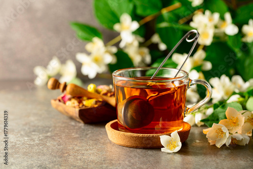 Quadro su tela Cup of jasmine tea and fresh jasmine flowers on a stone table.