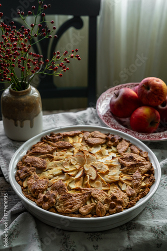 Homemade apple pie decorated with crust on wooden table in rustic kitchen.