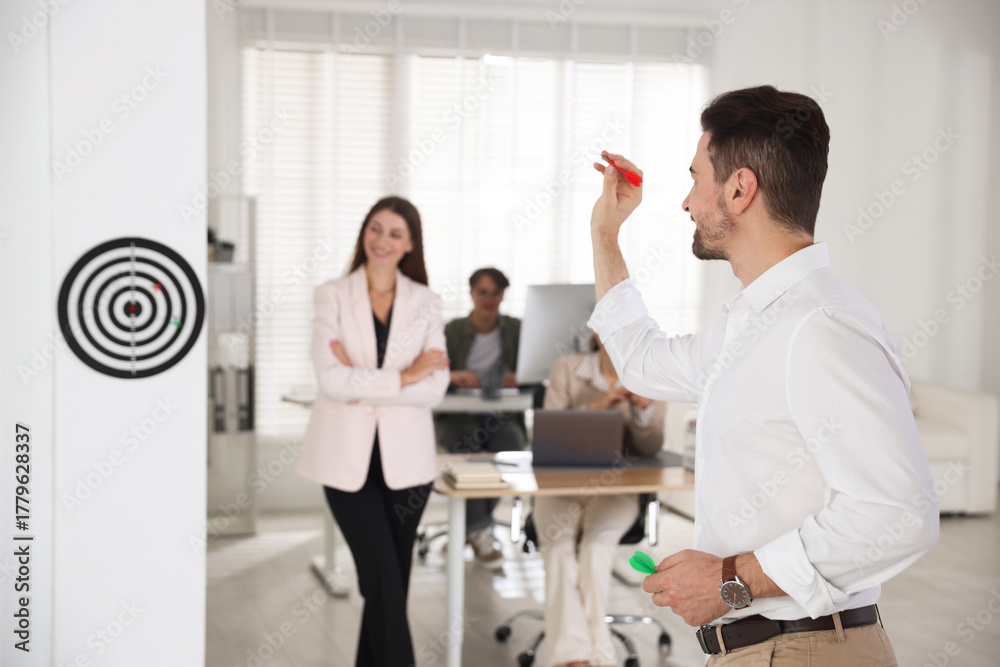 Obraz premium Group of colleagues playing darts in office, selective focus